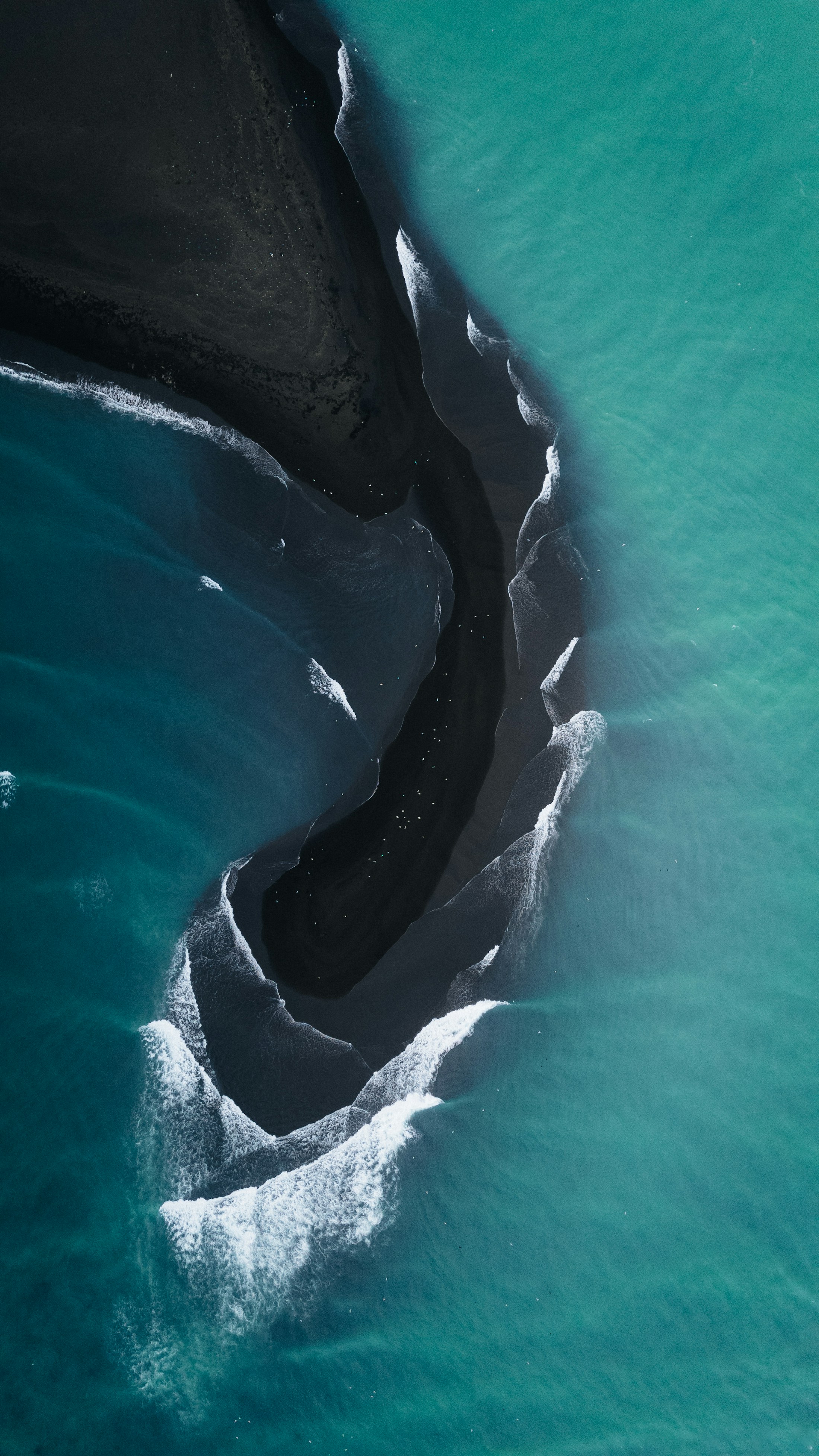 Aerial view of waves meeting Icelandic black sand